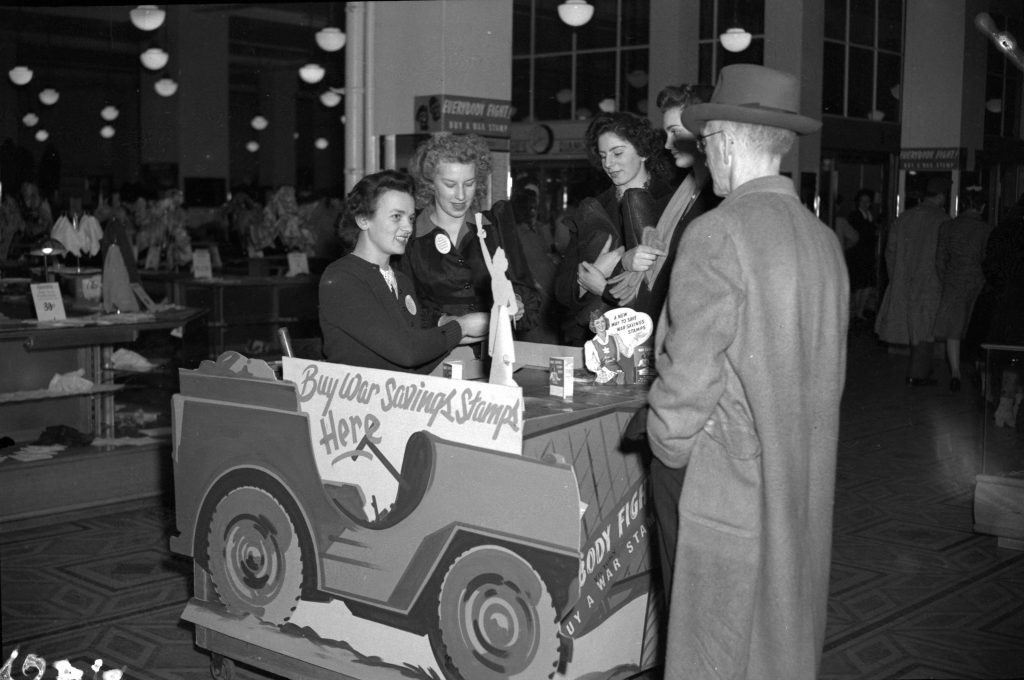 1940s vintage photo of people in 1940s hairstyles and 1940s fashions buy war stamps at Woodward's department store in Canada -1944