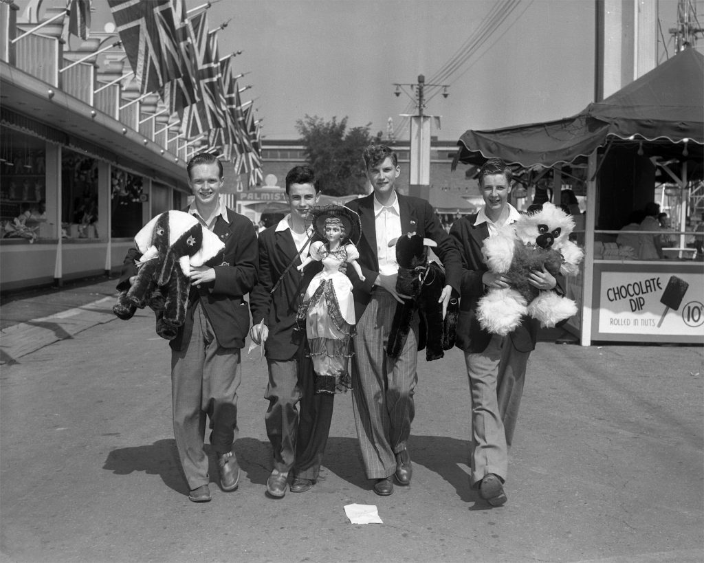 1950s vintage photo of CNE Visitors and their midway prizes in 1959. The image is a group of boys holding a doll and stuffed toys