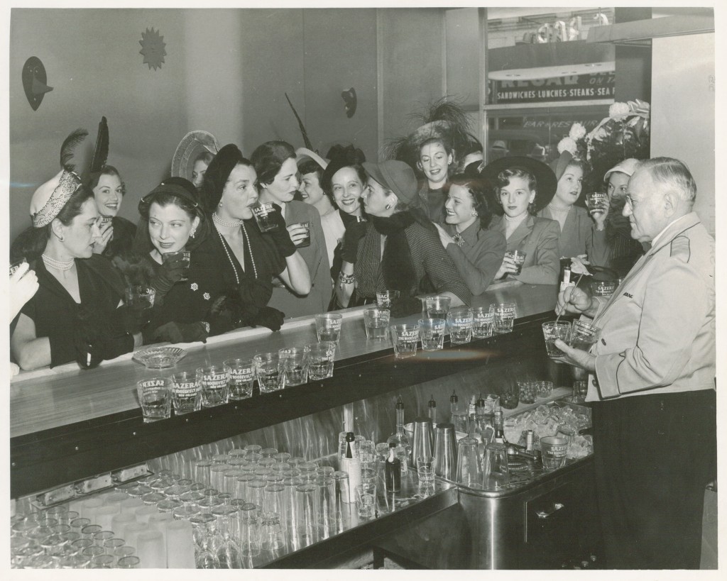 1940s vintage photo of women in 1940s fashions at a bar for the 'Storming the Sazerac' at The Roosevelt Hotel in 1949. ABOUT: Only men were served in the hotel’s classy Sazerac Bar—except for Mardi Gras day —but in 1949, a group of local women were thirsty and looking for sustenance. They stormed the Sazerac Bar demanding equality and a stiff drink.