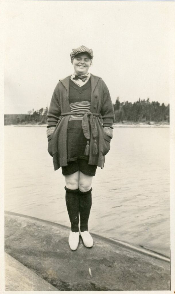 1920s vintage photo of a young woman in a 1920s bathing suit with her hands in the pocket of her cardigan. I like the mix of masculine and feminine in her look. 