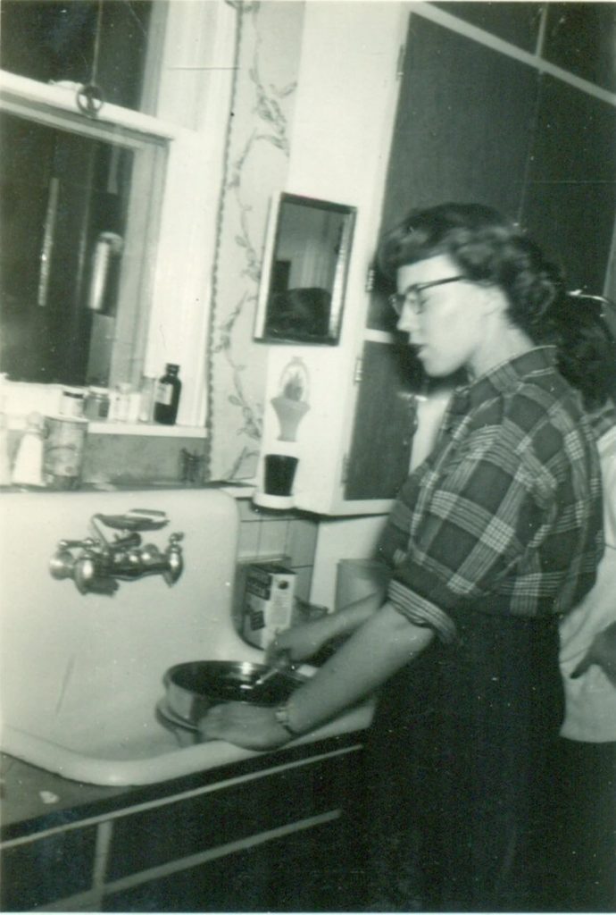 1950s vintage photo: 1950s Woman Washing Pan at Sink in a Plaid Shirt 