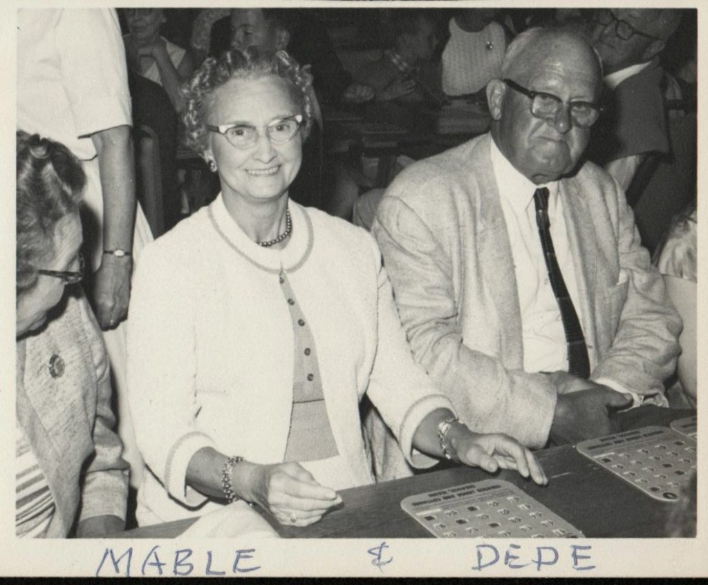 1960s vintage photo of an older couple playing Bingo. Their names are Mable & Dede. Love Mabels cat eye glasses and cardigan. Fun 1960s fashions. 