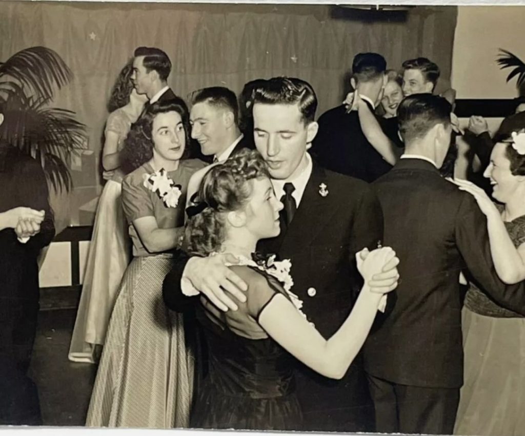 1940s vintage photo of a social dance featuring couples dancing together in 1940s fashions and 1940s hairstyles. 