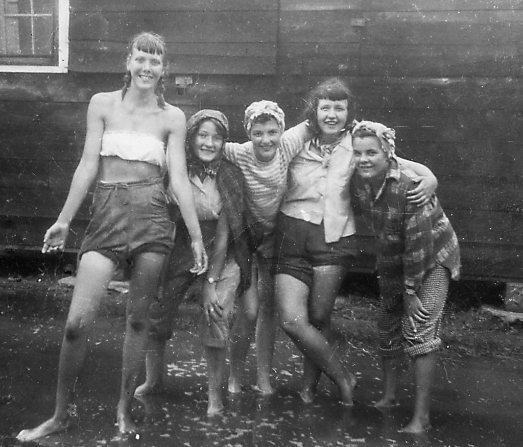 1940s photo of a group of girls playing in the rain taking a break from the farm in Ontario Canada. They were called Farmerettes and they helped feed Canadian soldiers during WW2