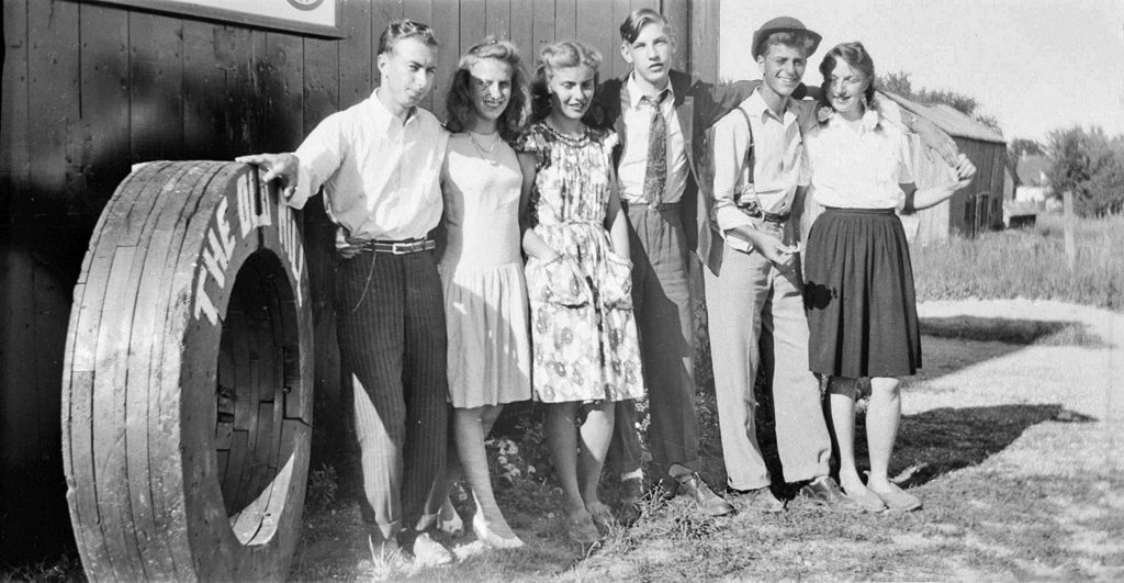 1940s vintage photo of young men and women in 1940s fashion in Ontario Canada heading out on a date. The girls were working on the farms to help the war effort and they were called 'Farmerettes'. 