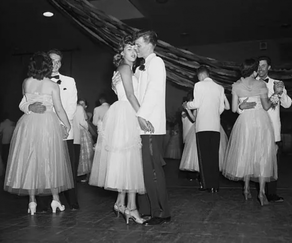 1950s vintage photo of a 1950s prom from 1953 featuring vintage prom dresses and young men in tuxedos. Photo description: 1953 photo of David Brandt and Ruth Estelle dancing at their Senior Prom at Anacosta High School.