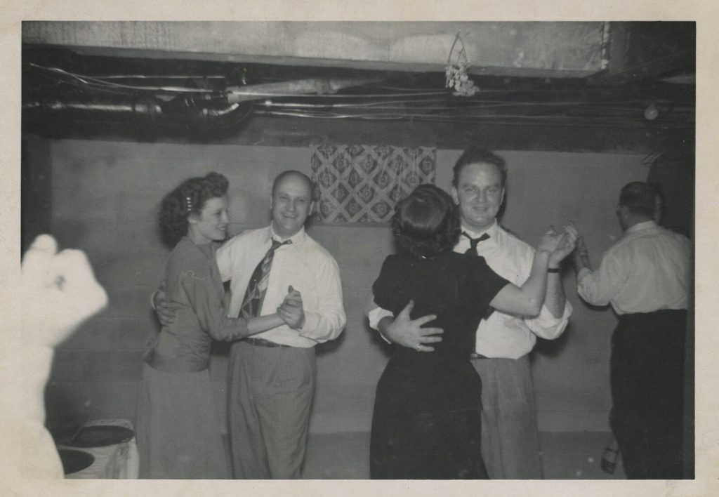 1950s vintage photo of a basement party featuring men and women dancing together in 1950s fashions