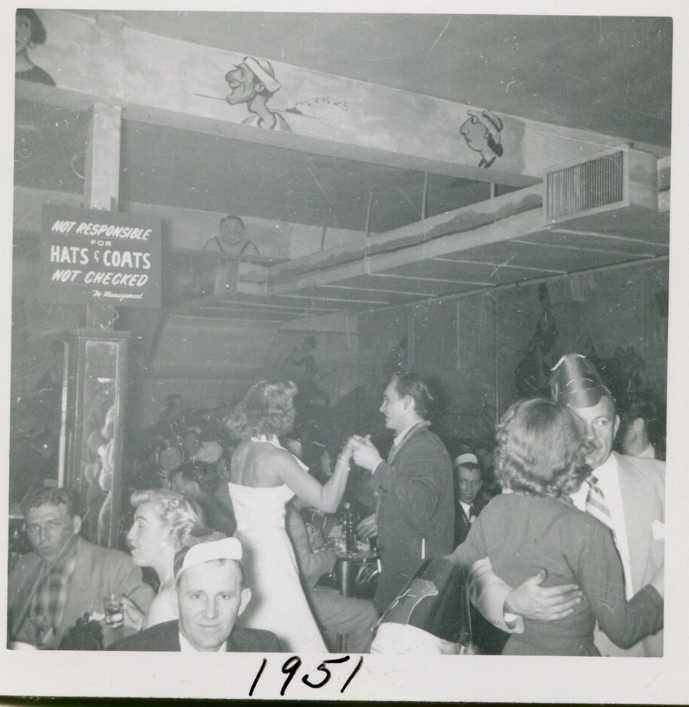 1950s vintage photo from 1951 of a bar on New Years eve with people dancing and celebrating.  Great early 1950s vintage hairstyles and fashions. 