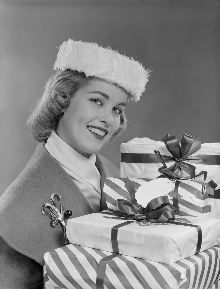 1950s vintage photo of a 1950s woman in a fur hat holding Christmas Presents and wearing a Christmas Brooch / Pin.