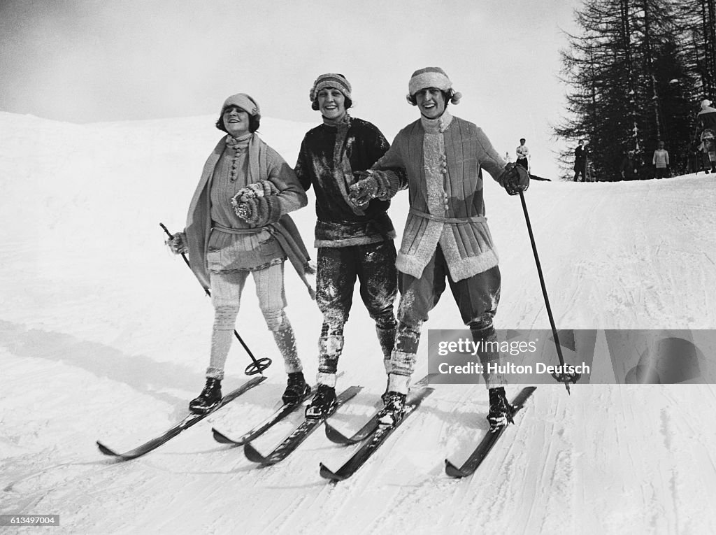 1920s vintage photo from 1924 of women in 1920s ski fashions skiing down the hill.