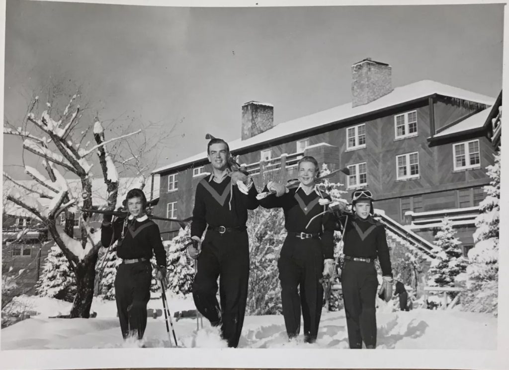 1950s vintage photo of a family in 1950s ski fashions outside of a ski resort getting ready to ski,