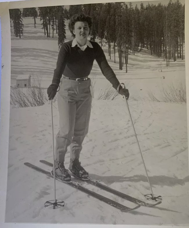 1950s vintage photo of a woman in a sweater and ski pants posing on skis. Fun vintage winter sport photo. 