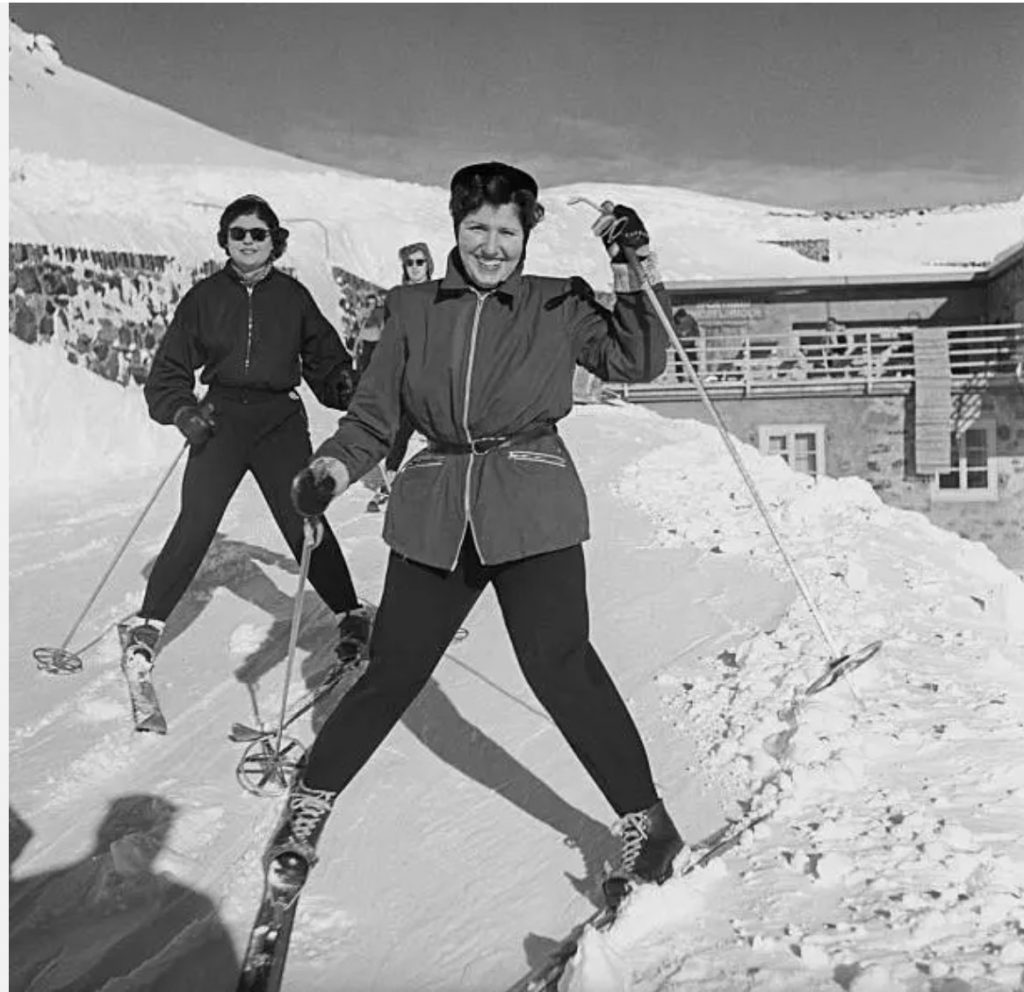 1950s vintage photo of two women downhill skiing in 1950s ski fashions